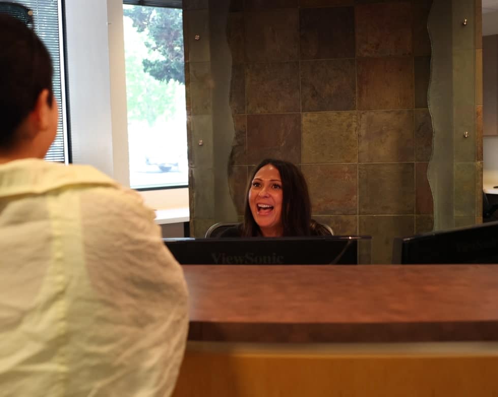 Front desk receptionist warmly welcoming a new patient with a friendly smile